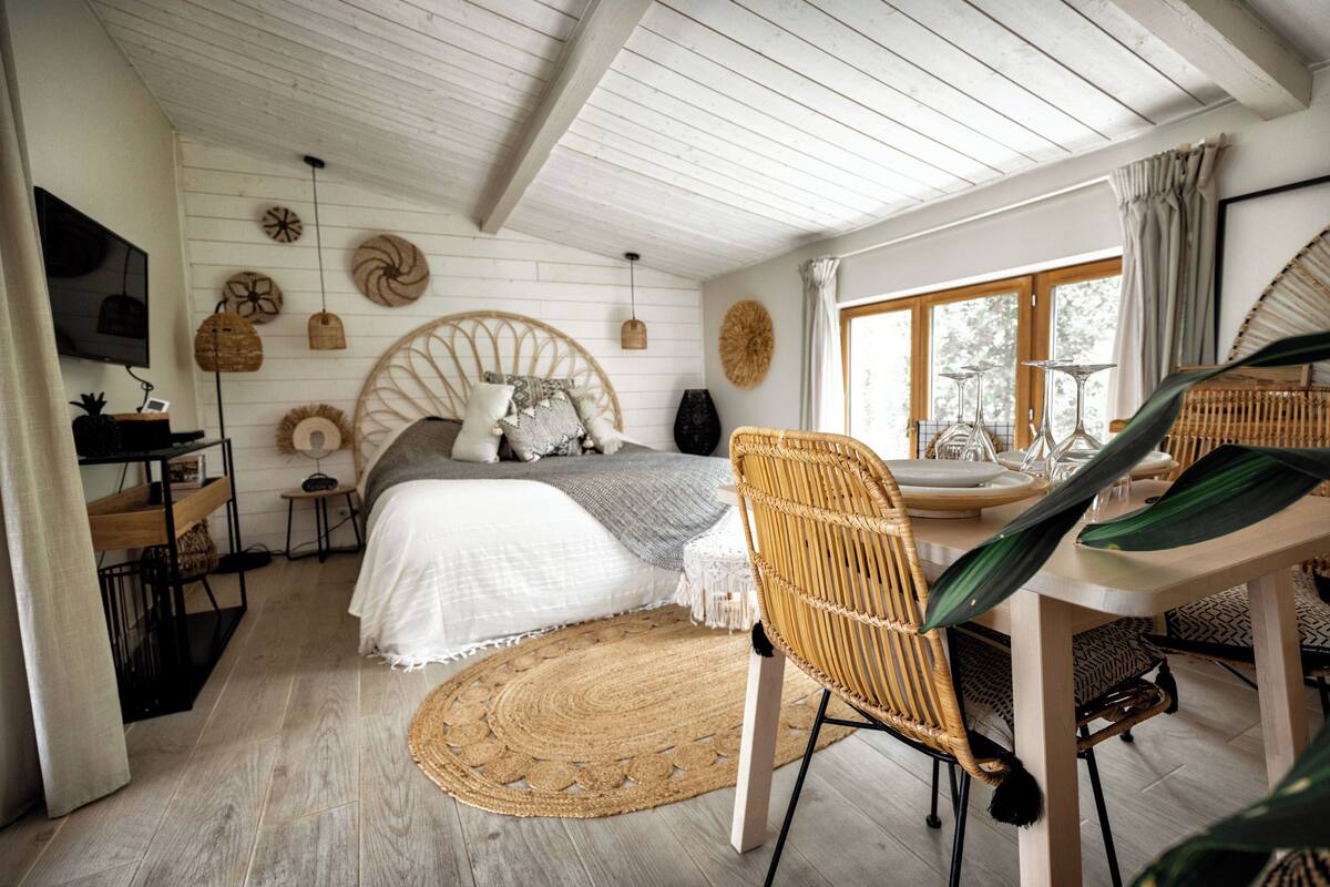 A bedroom with a bed, a desk, a chair, a dining table, and a window.