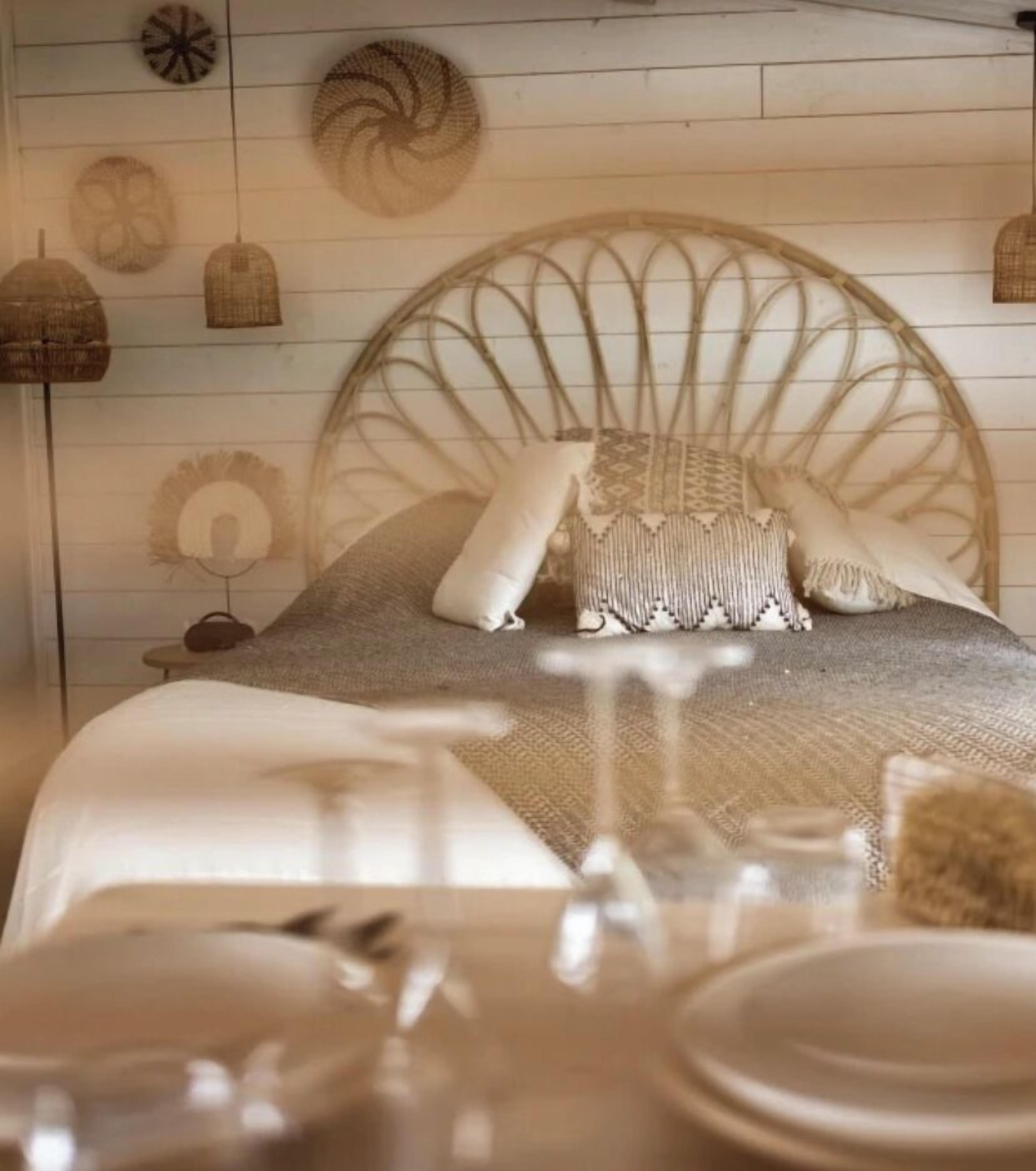 Una cama con cabecera trenzada, una manta estampada y almohadas.