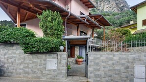Entrada de piedra a un edificio con un balcón de madera y una gran maceta.