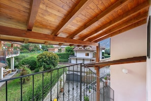 Ein Holzbalkon mit Steinboden, Blick auf eine Wohngegend und einem klaren Himmel.