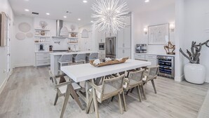 Una cocina moderna con una isla blanca, sillas de madera y una lámpara original.