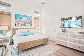 Ein Schlafzimmer mit einem Bett, einem Fernseher, einem Gemälde und einer Kommode.