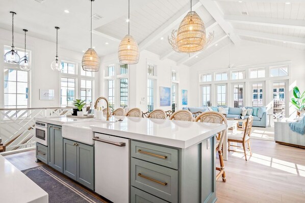 A spacious kitchen with a large island, pendant lighting, and a view to the living area.