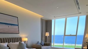 Une chambre d’hôtel moderne avec un grand lit, une vue sur l’océan et une grande fenêtre.