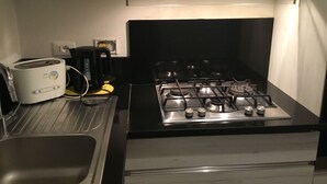 Une cuisine équipée d’une cuisinière à gaz, d’un grille-pain et d’une machine à café.
