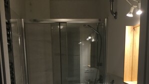 Une salle de bain moderne avec une douche à parois de verre, un lavabo blanc et un meuble en bois.
