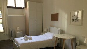 Une chambre à coucher comprenant un lit, des tables de chevet, une armoire, une petite table ronde et un tableau accroché au mur.