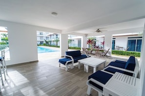 Relax in a comfortable outdoor lounge area with a pool nearby, featuring lounge chairs and a table.