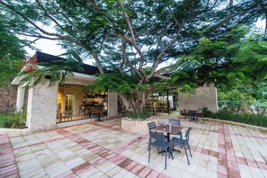 Enjoy dining al fresco in a shaded area surrounded by a tree and modern architecture.