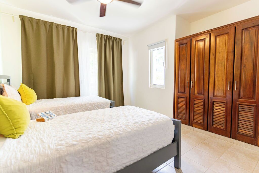 Una habitación de hotel con dos camas, un armario de madera y una ventana con cortinas.