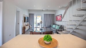 A modern living room with a glass dining table, a sofa, and a staircase. - TesCosy Beachfront 2 BDR Apartment. STM G406 (BAVARO)