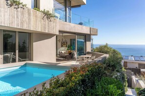 Una casa moderna con piscina, area relax all'aperto e vista mare.
