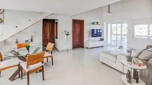 A spacious living area with a dining table and chairs, a sofa, and a TV. - Room Mare F-302  Share  Save (BAVARO)