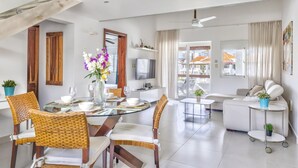 A modern living room with a dining area, a sofa set, a TV, and a balcony with a view. - Room Mare F-302  Share  Save (BAVARO)