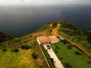 A modern house with a red roof, surrounded by a well-maintained lawn and a dirt path leading to the entrance.