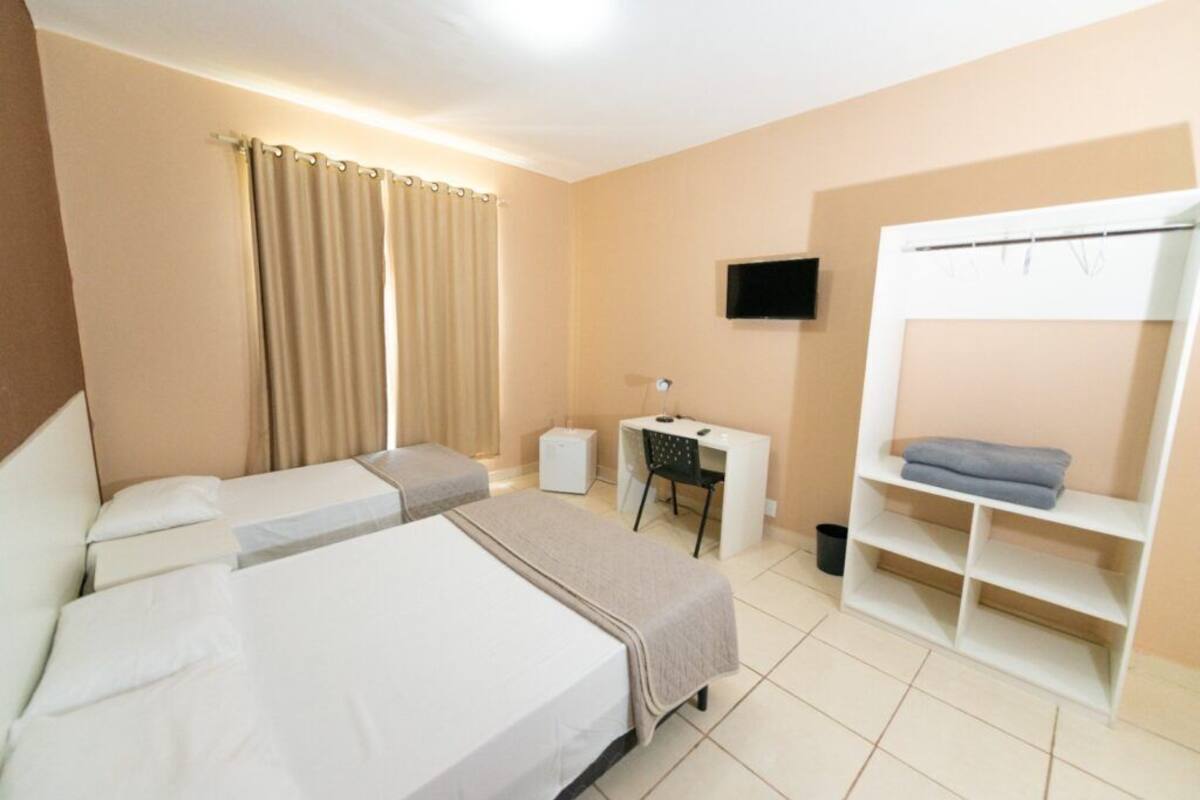 A hotel room with two beds, a desk, a television, and a wardrobe.