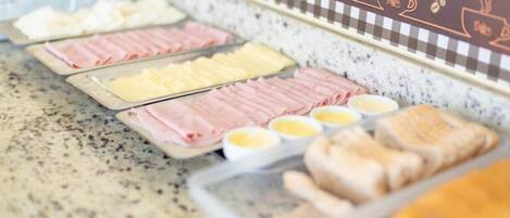 A buffet with various food items including sliced meats, cheeses, and eggs.