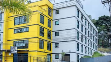 Two-story hotel building with a yellow and white facade, featuring rectangular windows and a prominent entrance.