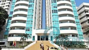 Un moderno edificio de gran altura con varios balcones y una entrada central.