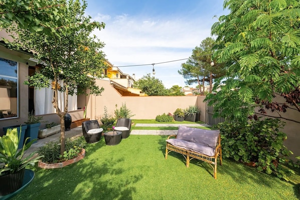 A well-maintained garden with a lawn, outdoor furniture, and a variety of plants.