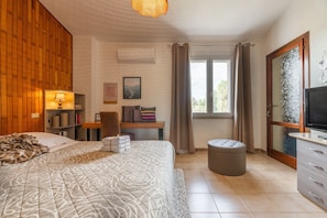 A bedroom with a bed, a desk, a chair, a television, and a window with curtains.