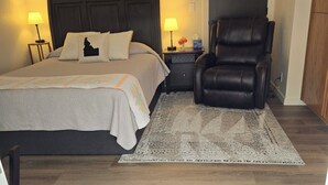 A bedroom with a bed, a chair, a rug, and artwork on the wall. - Charming studio in fabulous Meridian, Idaho with WiFi, AC, Private entry. (Meridian)