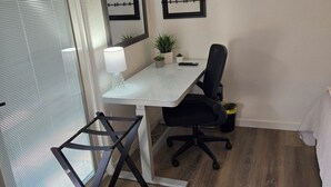 A modern office space with a white desk, black office chair, and a large flat-screen TV mounted on the wall. - Charming studio in fabulous Meridian, Idaho with WiFi, AC, Private entry. (Meridian)