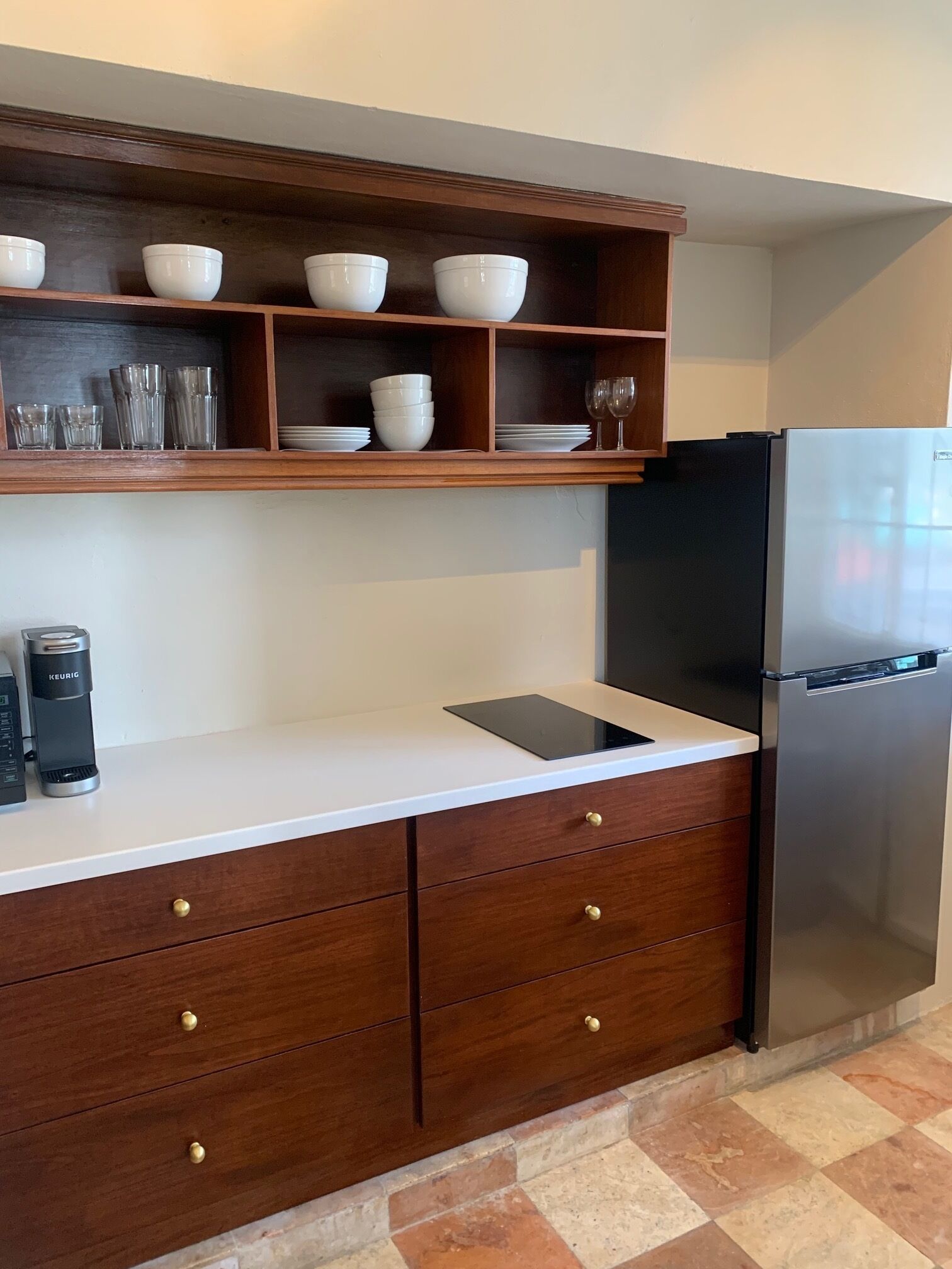 A kitchen with a white countertop, wooden cabinets, a black refrigerator, and a coffee maker.