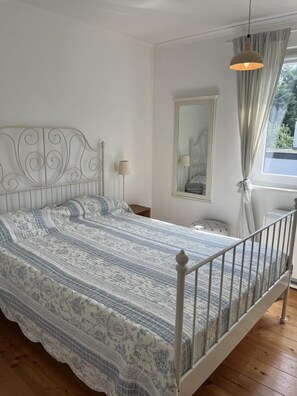 Cozy retreat with a single bed, bedside table, and window overlooking lush greenery.