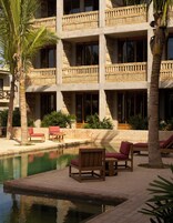 Un hotel con zona de piscina, varios balcones y mobiliario exterior.