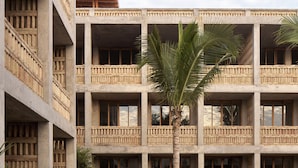 Ein mehrstöckiges Hotel mit Balkonen, einem Poolbereich mit Liegestühlen und einem Weg zum Pool.