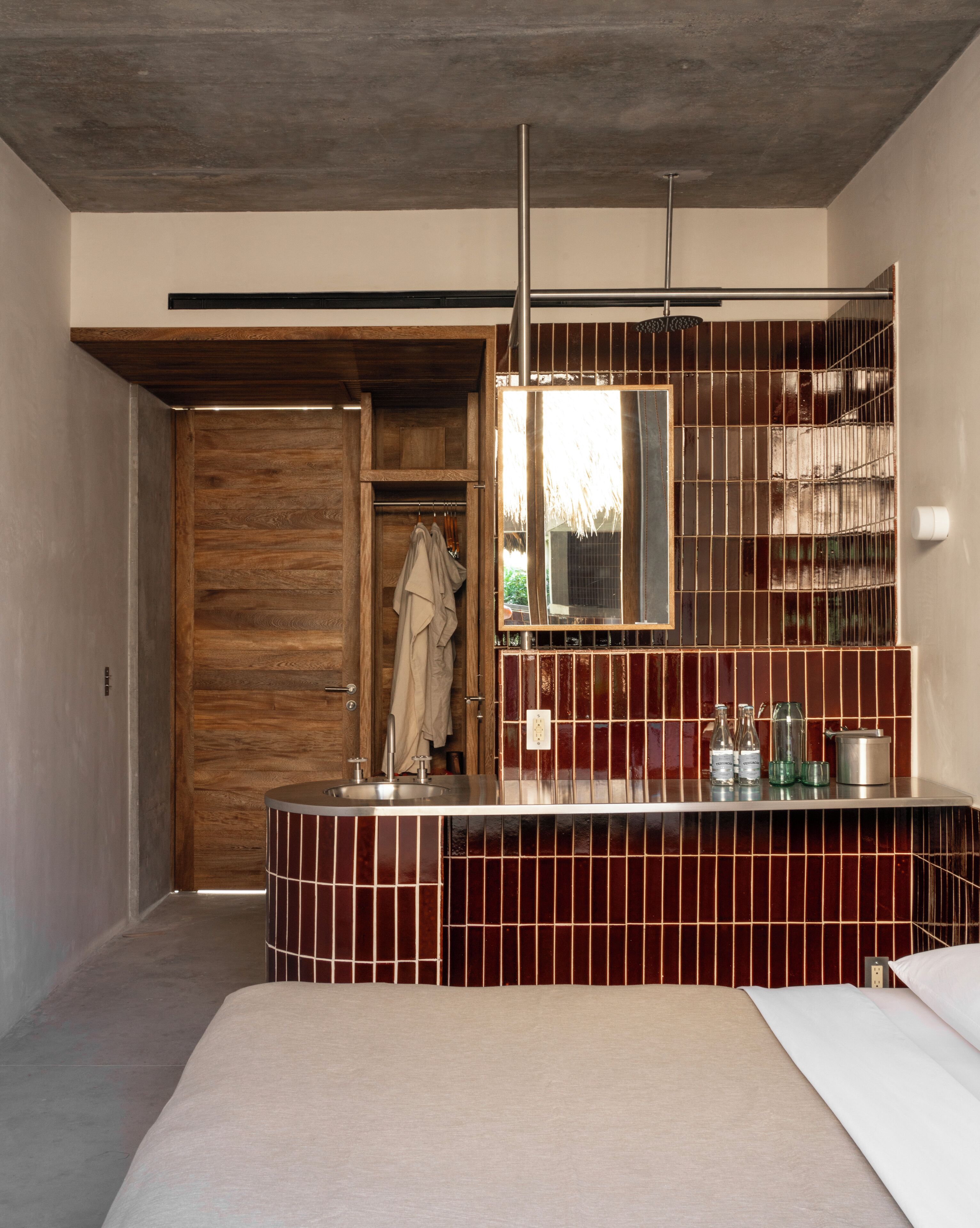 Ein modernes Badezimmer mit Holztür, großem Spiegel und Fliesenwaschtisch.