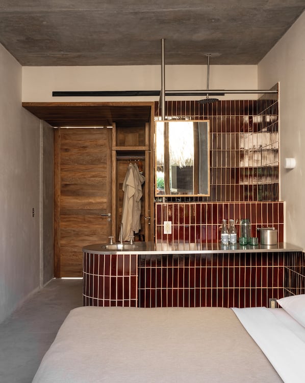 A modern bathroom with a wooden door, a large mirror, and a tiled vanity.