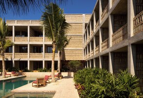 Un hotel con piscina, mobiliario exterior y palmeras.