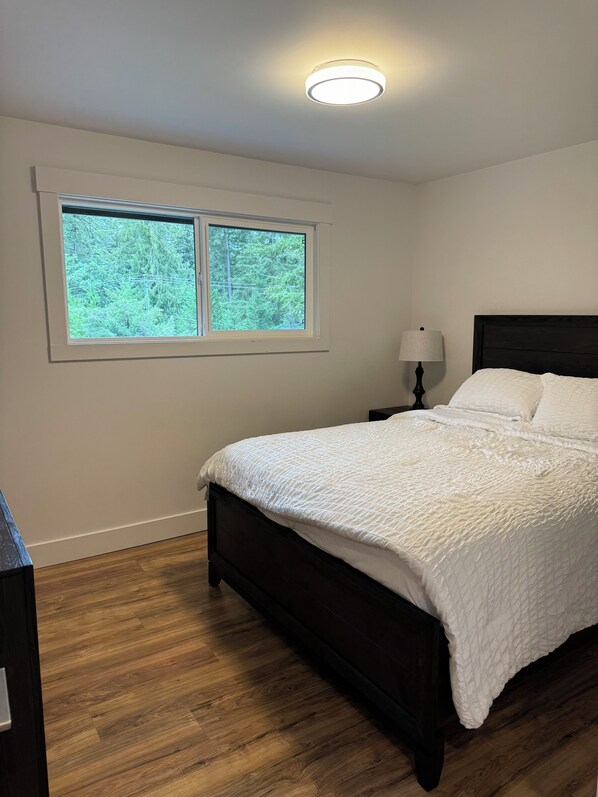 A bedroom with a bed, a window, a nightstand, and a lamp.