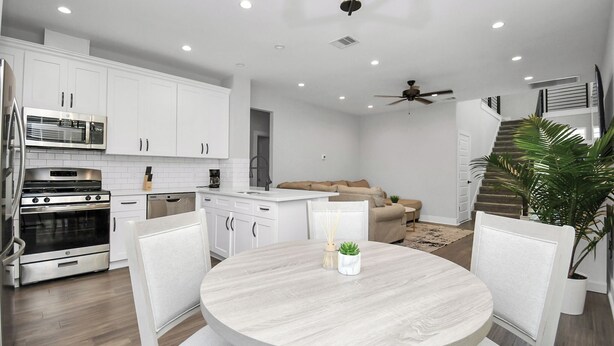 A modern kitchen with white cabinetry, a dining table, and a ceiling fan. - Cozy & Stylish Family Friendly in Gated Community (Sugar Land)