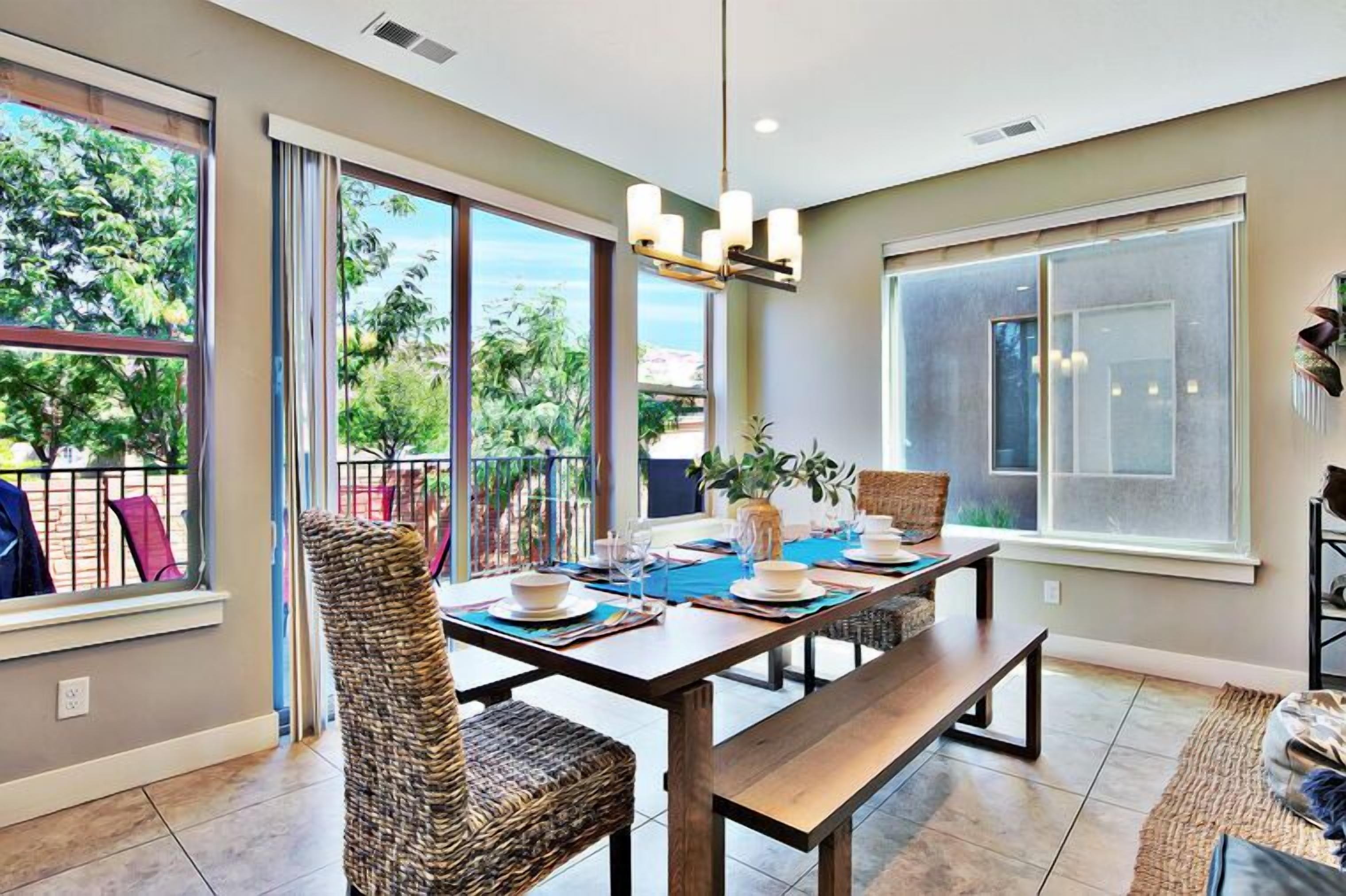 A dining area with a table, chairs, and a view through large windows.