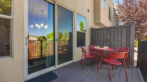 A patio with a table and chairs, a sliding glass door, and a wooden fence.