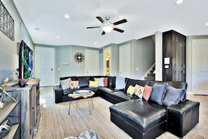 A modern living room with a sectional sofa, a coffee table, and a ceiling fan.