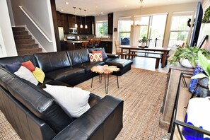 A modern living room with a black leather sofa, a dining table, and a kitchen in the background. - Entrada at Moab 620 and 624 (Moab)