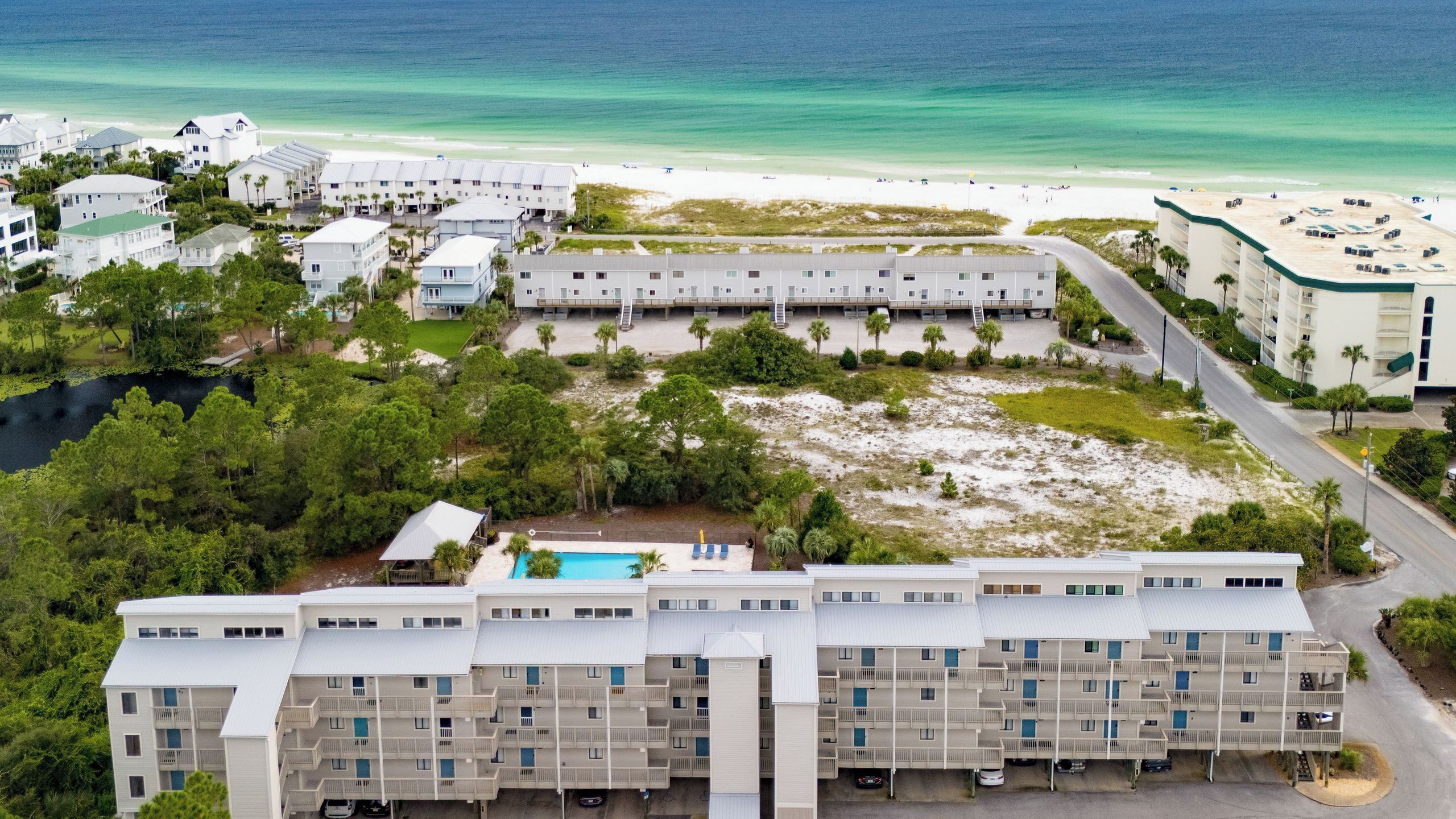 Un complexe hôtelier comprenant plusieurs bâtiments, une piscine et offrant une vue sur la plage.