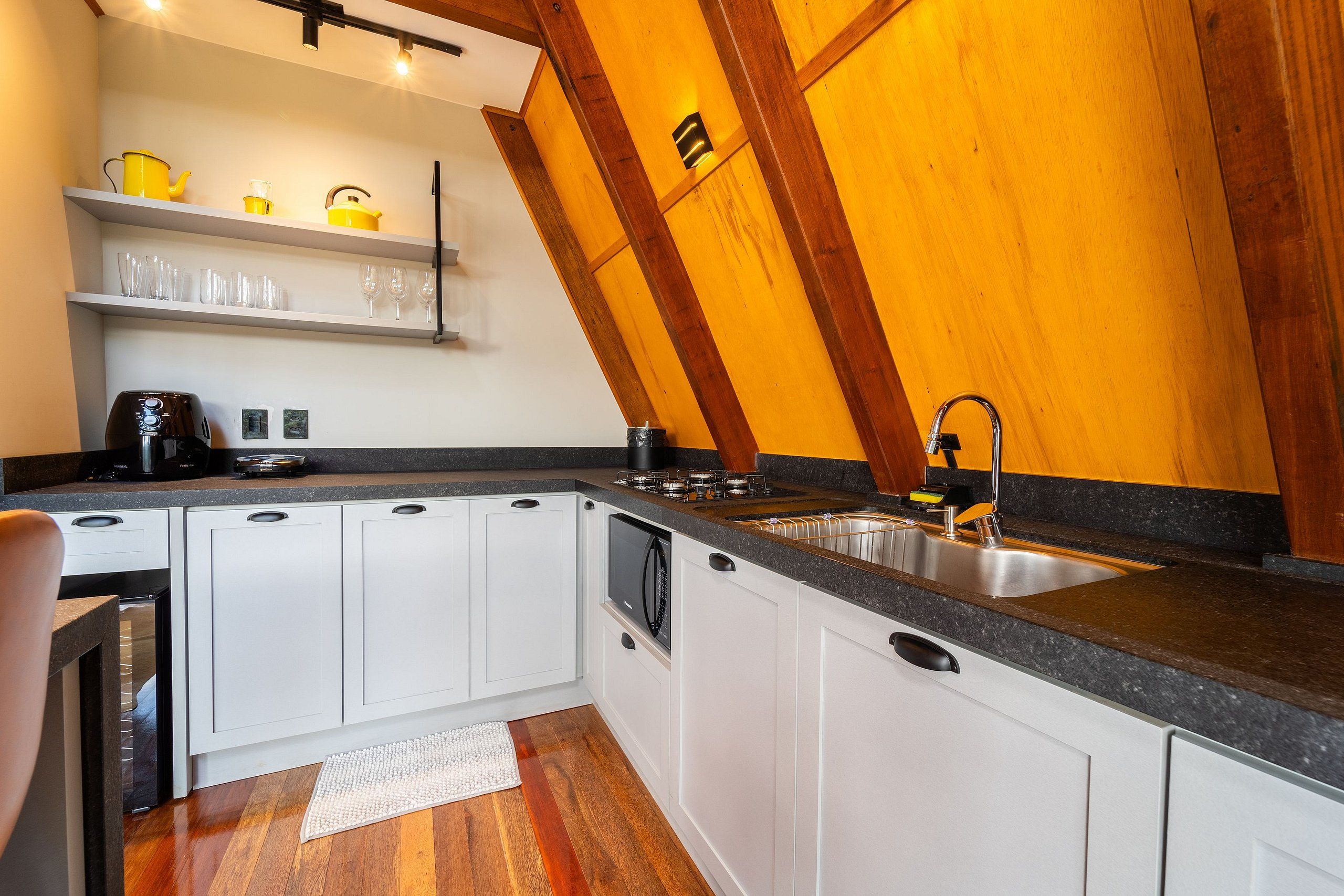 A modern kitchen with white cabinets, a granite countertop, and a wooden ceiling.