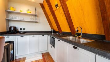 A modern kitchen with white cabinets, a granite countertop, and a wooden ceiling.