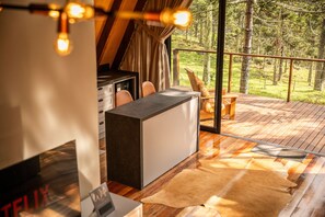 A cozy cabin interior with a wooden deck, a large window overlooking a forest, and a leather rug on the floor. - Pousada Refúgio da Boa Vista (Urubici)