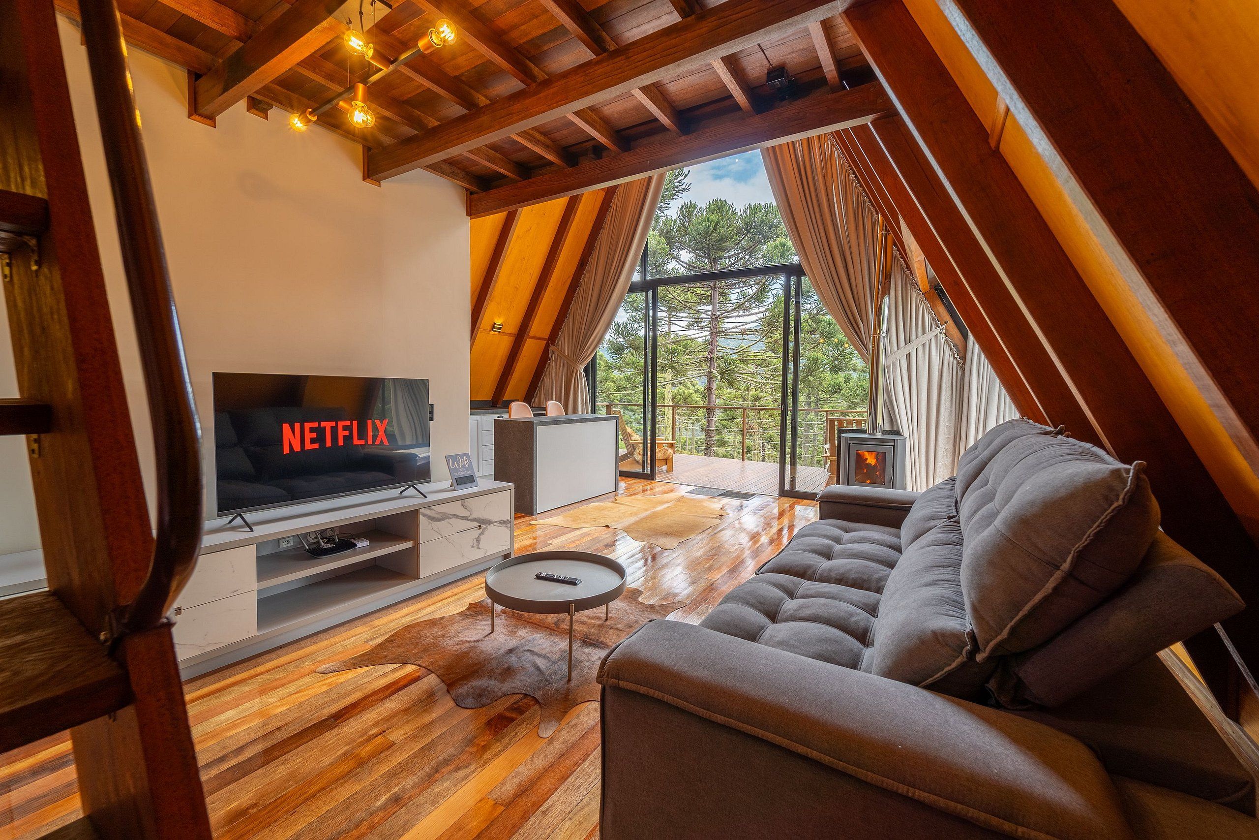 Un salon moderne avec un téléviseur affichant le logo « NETFLIX », un canapé, une table basse et une cheminée.