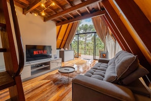 A modern living room with a television displaying 'NETFLIX', a sofa, a coffee table, and a fireplace. - Pousada Refúgio da Boa Vista (Urubici)