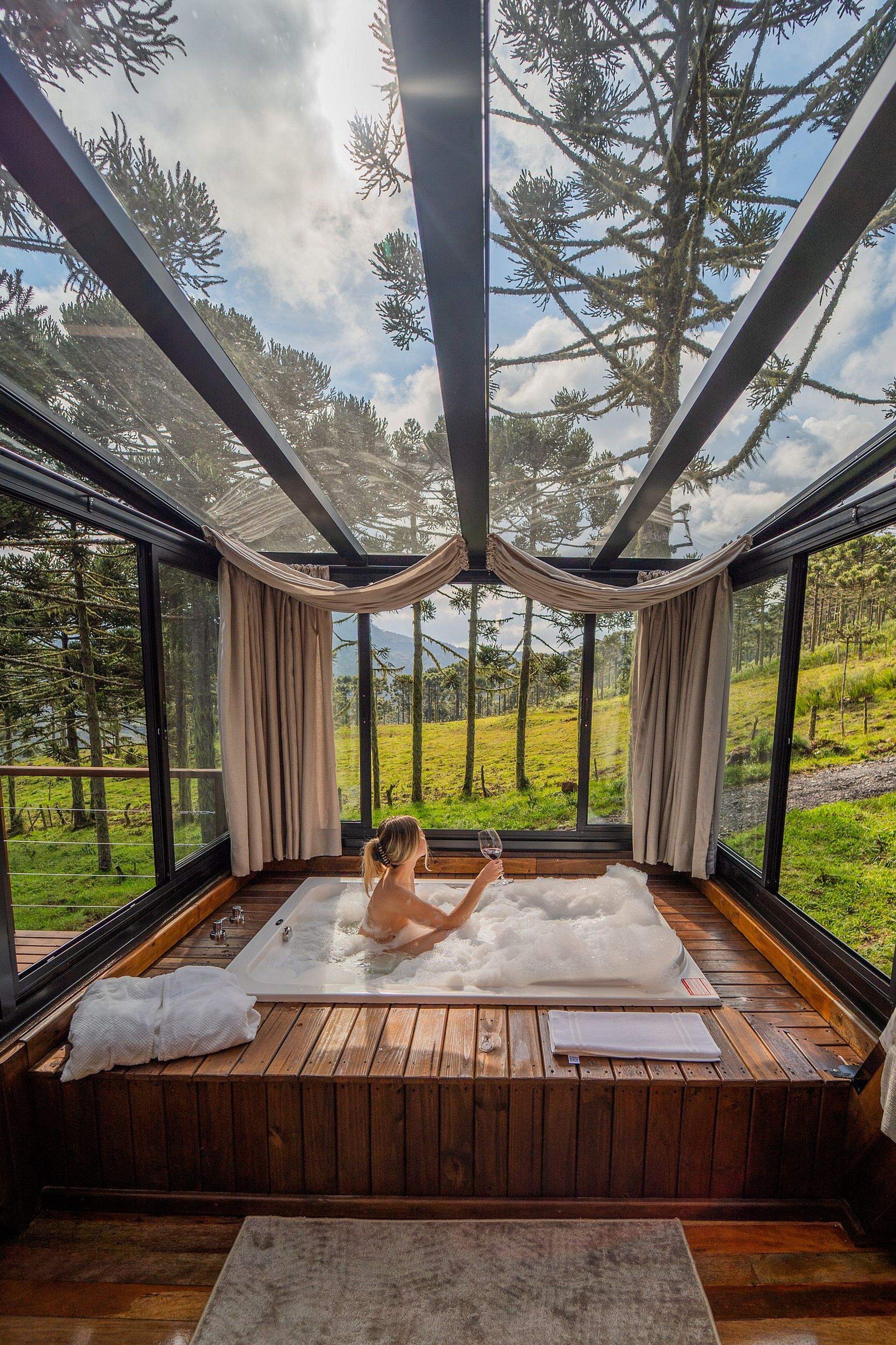 A spa room with a wooden floor, a large window, and a view of a forest.