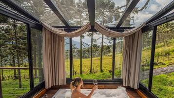 A spa room with a wooden floor, a large window, and a view of a forest.