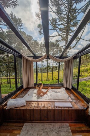 A spa room with a wooden floor, a large window, and a view of a forest.
