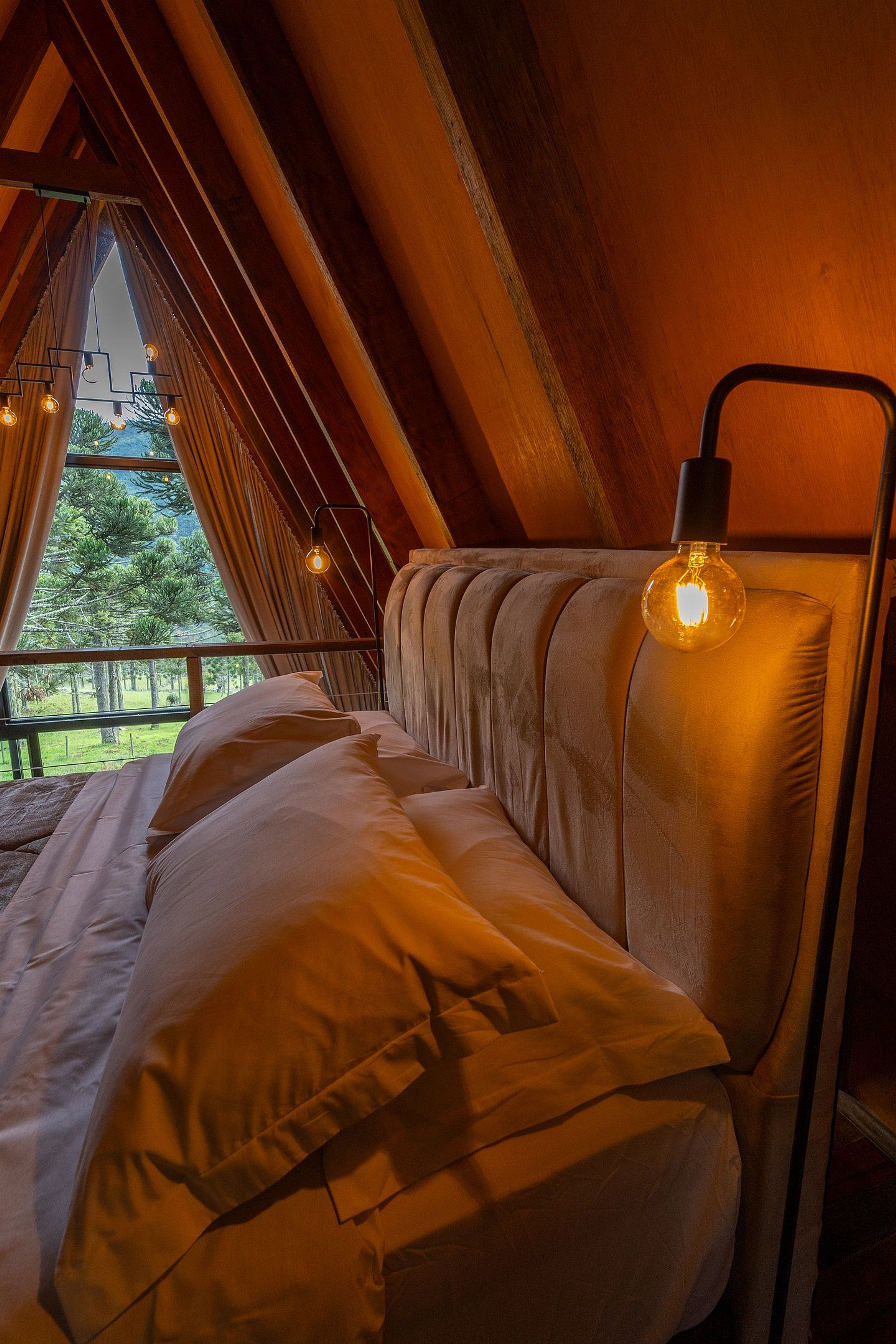 A cozy bedroom with a bed, a hanging light fixture, and a window with curtains.